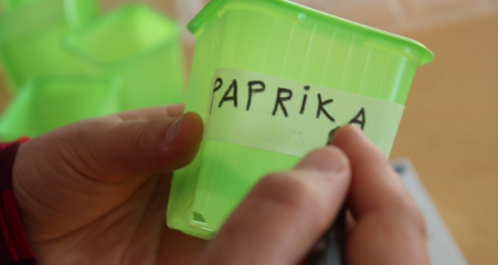 UMAKO-kurssin opiskelija kirjoittaa idätyspurkin kyljessä olevaan teippiin 