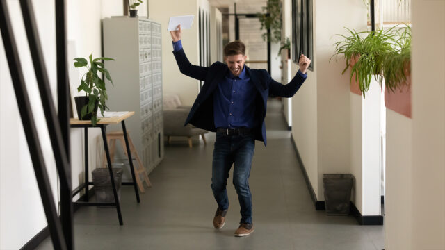 Mies tuulettaa käytävässä onnistuneen työhaastattelun jälkeen.