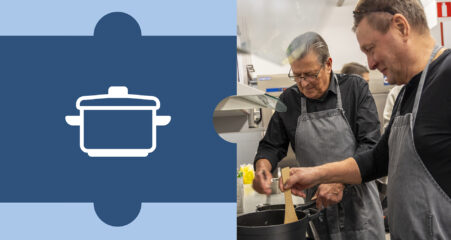 Kaksi miestä laittaa ruokaa lieden ääressä.